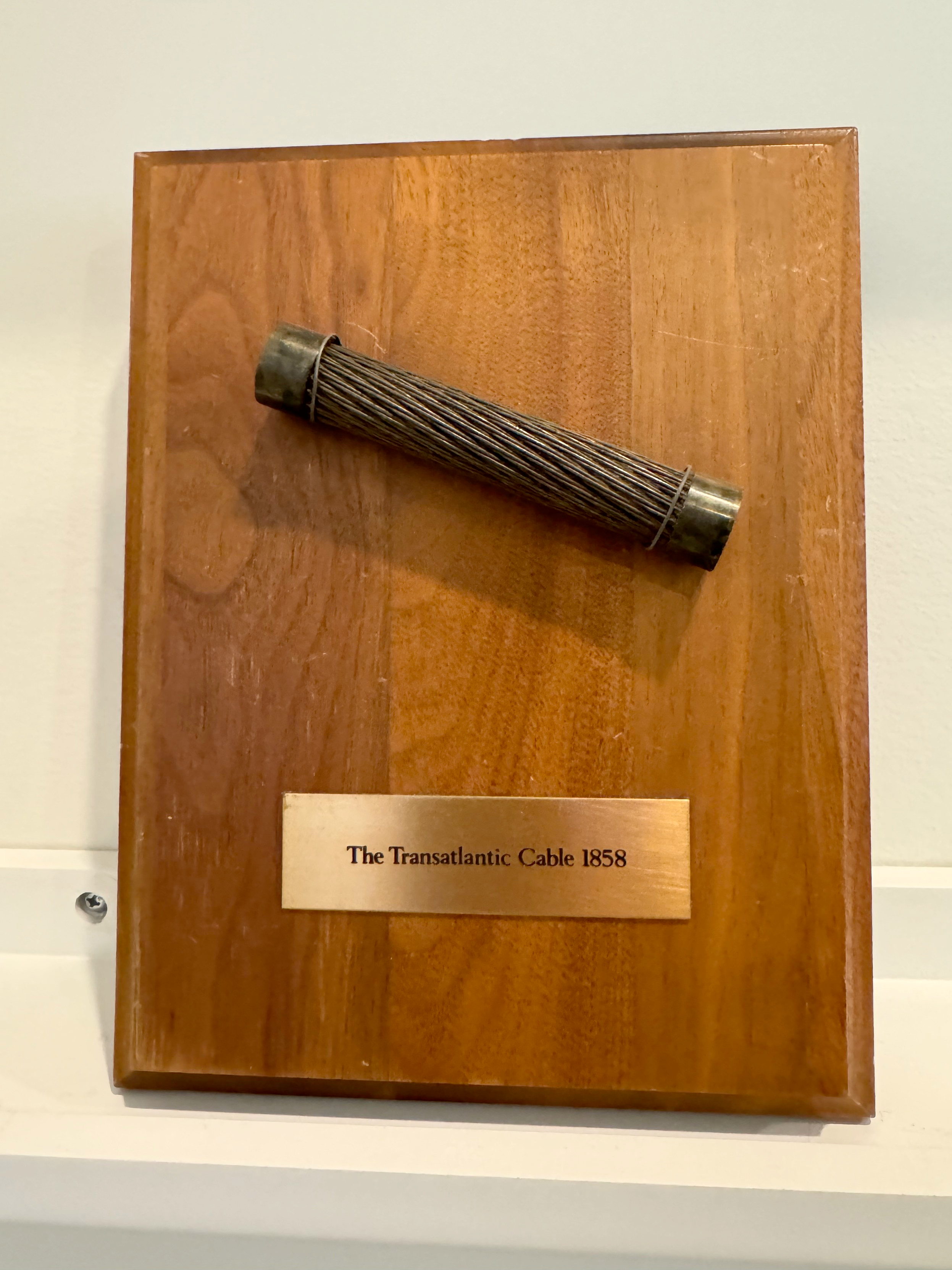 a piece of the first transatlantic telegraph cable mounted on a plaque labeled The Transatlantic Cable, 1858